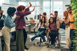 Young diverse business people racing in an office chair race at work having fun and enjoying themselves in the workplace to create a happy work culture and productive teams that work together to achieve success team work creativity