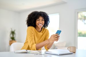 Happy young African American woman at home using mobile phone. Portrait. medical aid young professional