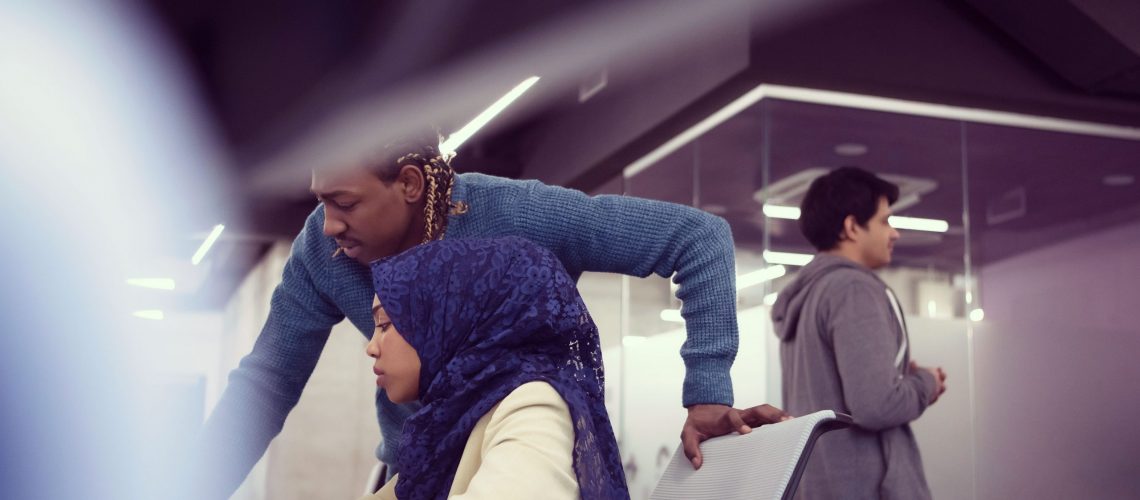 black muslim female software developer working together with her african american male colleague using computer while writing programming code at modern startup office