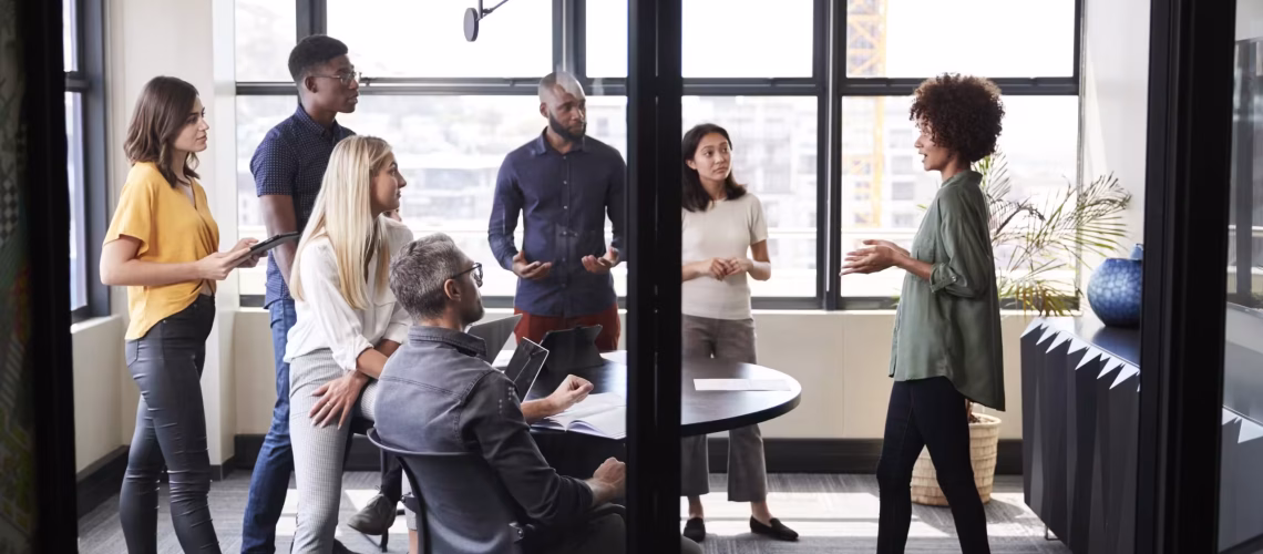 Creative business team listening to their female colleague presenting at a brainstorm meeting