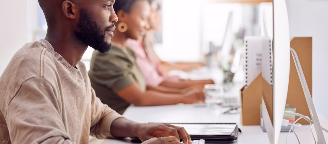 Shot of a businessman working on his computer while his colleagues sit in the background and work readiness