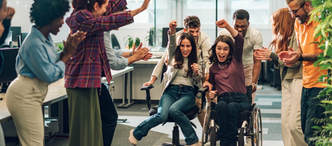 Young diverse business people racing in an office chair race at work having fun and enjoying themselves in the workplace to create a happy work culture and productive teams that work together to achieve success team work creativity