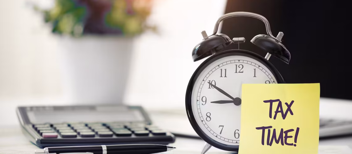 tax time sign on a post it with a clock and calculator and pen