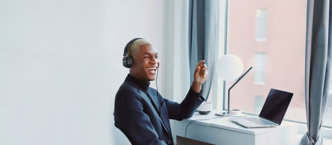 employee working on a laptop remote working at home with headphones while smiling