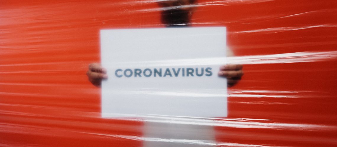 man-behind-a-plastic-holding-a-poster-of-coronavirus-3952185