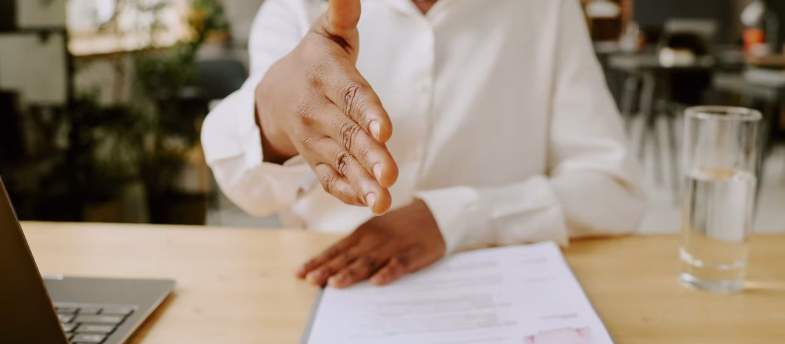 a female employee holding out her hand to shake a new recruit from their hiring process in the workplace