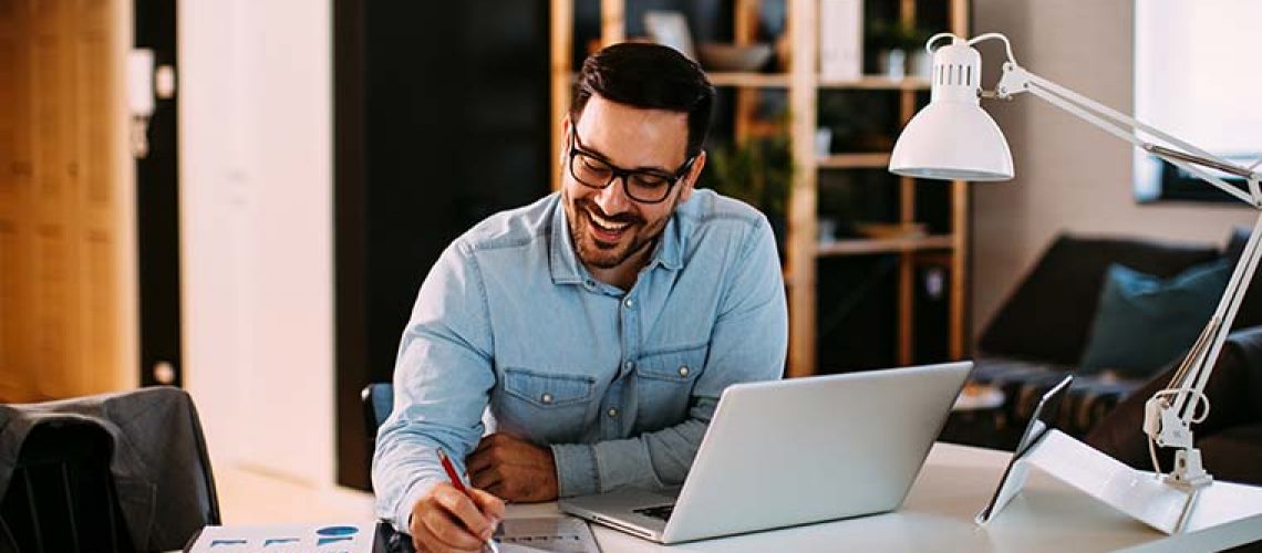 Young business man working at home with laptop and papers on desk