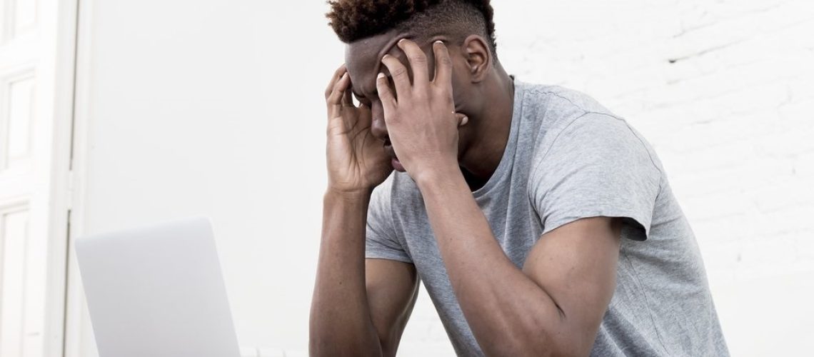 stressed_employee_at_his_desk_holding_head wellness wellbeing mental health coping strategies calm balance unhappy