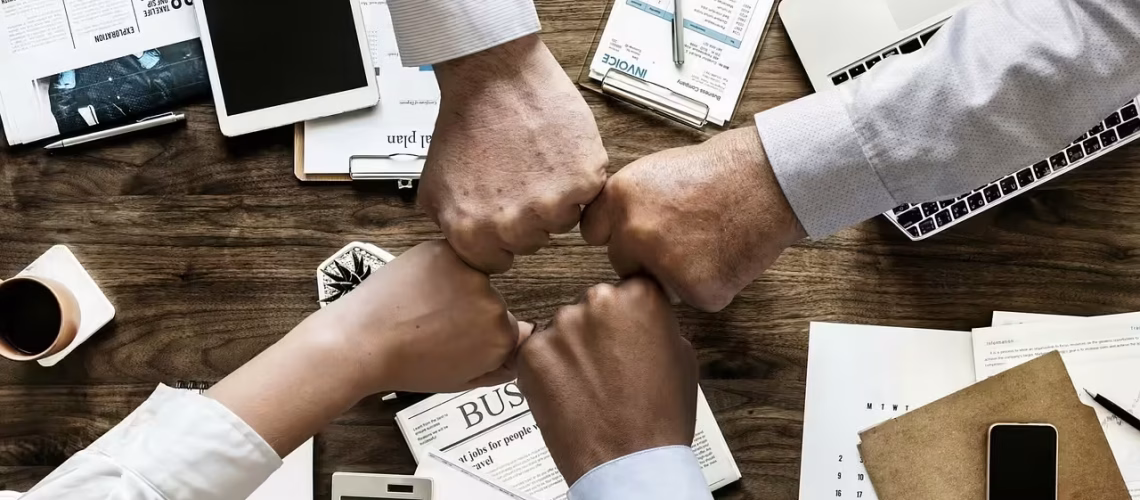 team meeting of hands in together at a company board table showing the company culture of a healthy wellbeing and great attention to company and employee wellness to boost productivity