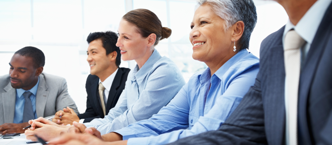 A team of executives at a board meeting. The team is made up of a diverse set of talent that all participate with the same goal in mind while considering all angles of the business senior employees